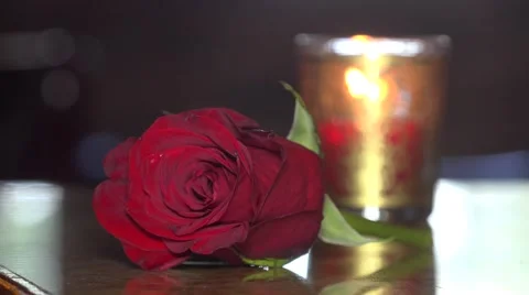 Red Rose Laying On Table Next To Burning Orange candle Stock Footage 56729641