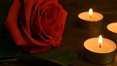 A red rose lies on a table and three candles are burning Video stock 123484751