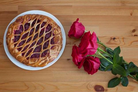 Red roses and berry pie on the wooden table Stock Photos