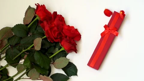 Red roses and present box on white table. Slow motion. Holiday background. Stock Footage 102836653