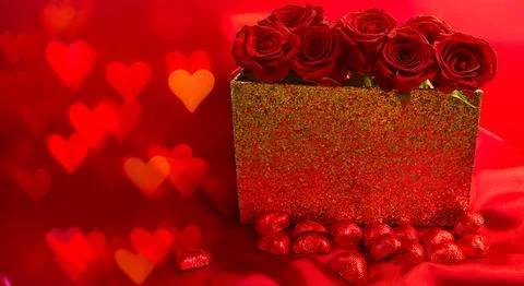 Red roses in a gift box on red background with chocolate hearts Stock Photos