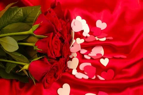 Red roses on a red background with pink and white hearts scattered around Stock Photos