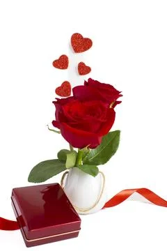 Red roses in a small white vase with a red jewelry box and a red silk bow. Stock-Fotos