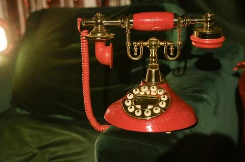 Red rotary phone with brass elements, placed on a velvet green surface. pho.. 库存照片