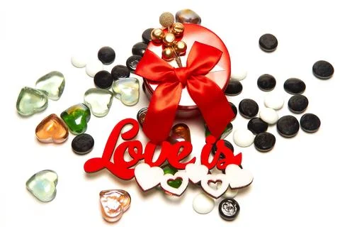 Red round box with a bow and decoration on top, the inscription love is, whit Stock Photos