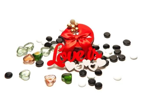 Red round box with a bow and decoration on top, the inscription love is, whit Stock Photos