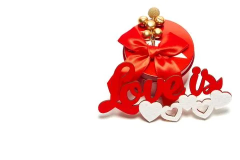 Red round box with a bow and the inscription love is with white hearts on a w Stock Photos