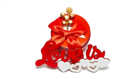 Red round box with a bow and the inscription love is with white hearts on a w Stock Photos