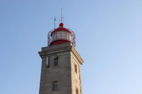 Red round lighthouse top on a square stone tower 스톡 사진