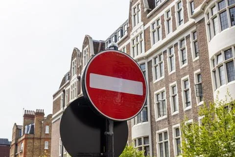 Red round no entry traffic sign positioned outdoors on an urban street near b Stock Photos
