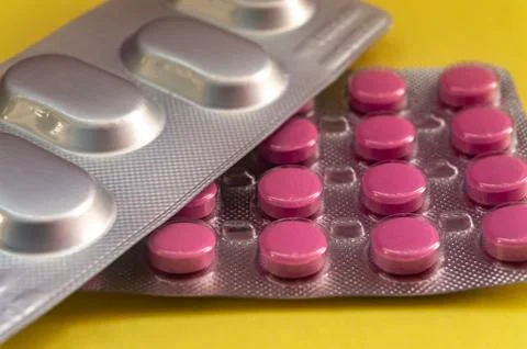 Red round tablets, oval tablets on a yellow background Stock Photos