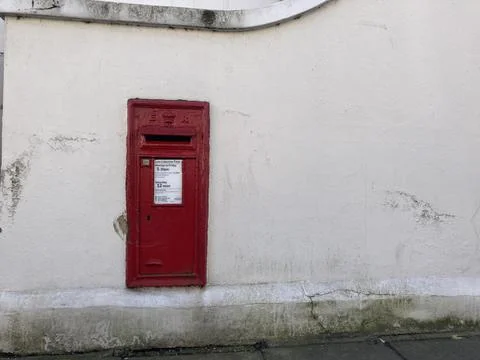 Red Royal Mail Post Box on White Wall Stock Photos