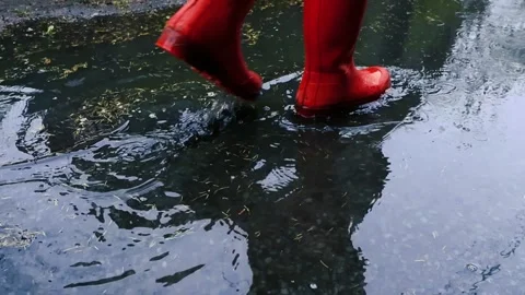 Red Rubber Boots Splashing in a Puddle During Rain, Slow Motion Stock Footage 335132879