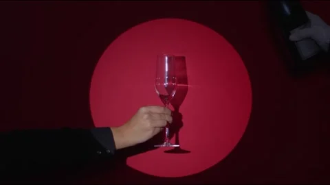 Red ruby background. A hand holds a glass in the spot light, waiter hand serving Stock Footage 146169044
