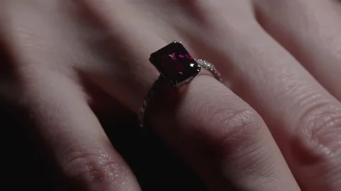 Red ruby diamond engagement ring on woman's finger. Light sweeping over Stock Footage 234994041