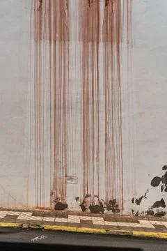 Red rusty water dripping down a white wall Stock Photos
