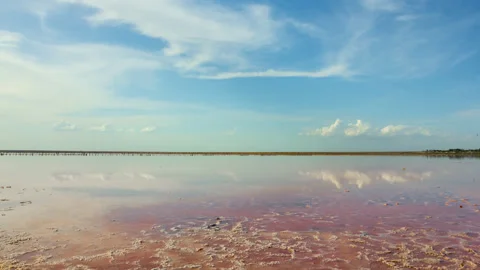 Red saline lake under a cloudy sky, summer time lapse scene Stock Footage 133988591