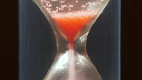 Red sand in hourglass, time flows backwards, in opposite direction Video stock 277137079