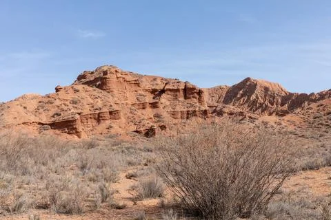 Red sandstone cliffs and arid steppe landscape in Mars Canyon, Kyrgyzstan Stock Photos