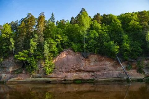 Red sandstone cliffs by the river in Gauja national park in Latvia Stock Photos