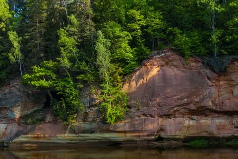 Red sandstone cliffs by the river in Gauja national park in Latvia Stock Photos
