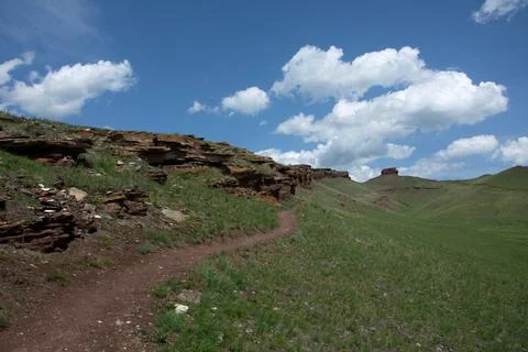 A red sandstone path leads to the top of a beautiful hill set against a backdrop Stock Photos
