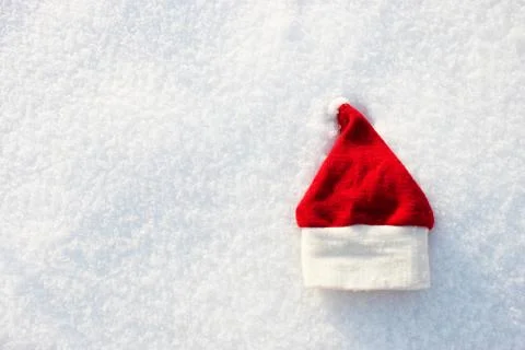 Red Santa hat and knitted mittens lie on the snow. mitten lying on the snow in Stock Photos