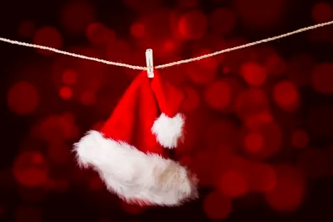 A red santa hat hanging on a string with defocused lights Stock Illustration