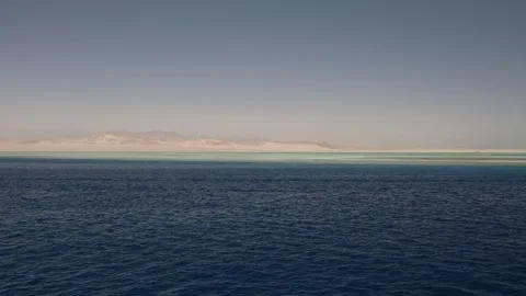 Red Sea layers deep blue water turquoise shallows golden desert distant haze mou Stock Footage 310819409