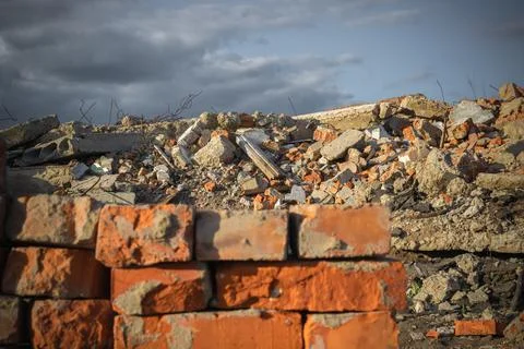 Red selected bricks on the background of a destroyed building and blue sky. Stock Photos