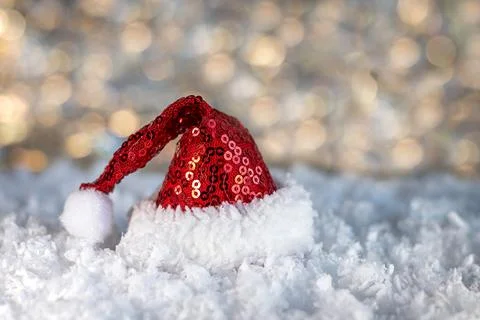 Red sequin Santa hat resting on snowy ground creating a festive Christmas mood Stock Photos
