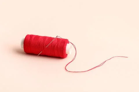 Red sewing thread with needle on beige background Stock Photos