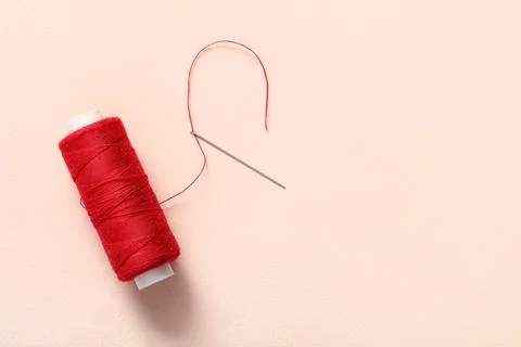 Red sewing thread with needle on beige background Stock Photos