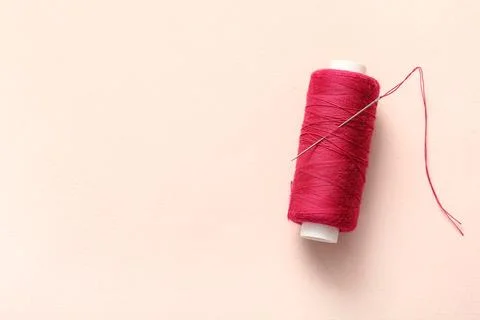 Red sewing thread with needle on beige background Stock Photos