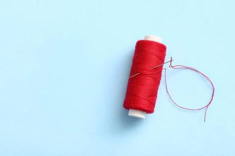 Red sewing thread with needle on blue background Stock Photos