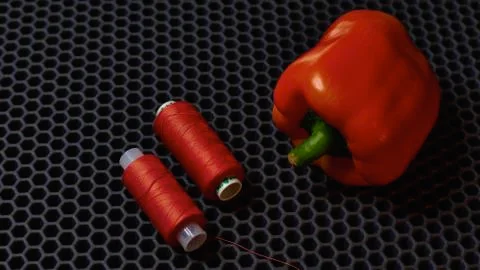 Red sewing threads and red bell pepper on a dark background close-up from above Stock Photos