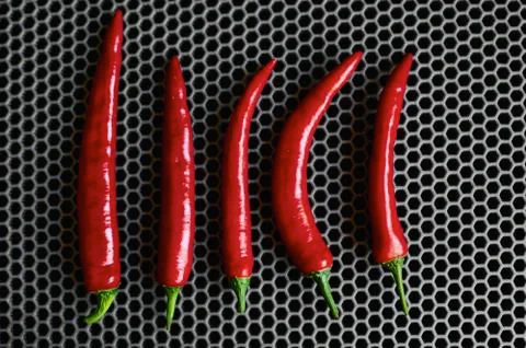 Red sharp chili peppers vertically top close up against a dark background Stock Photos