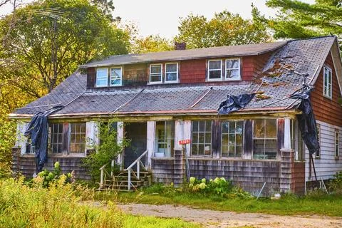 Red shingles falling off old abandoned house with black tarp broken shingles and Stock-Fotos