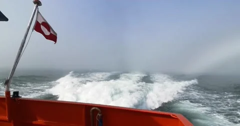 Red ship floating in white fog with the Greenland flag on the stern Video stock 148198225