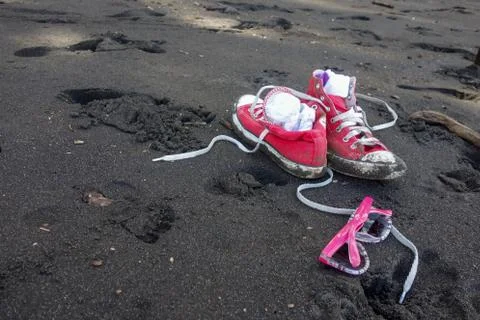 Red shoes and girls sunglasses on Waipio Valley black sand beach, Hawaii Stock Photos