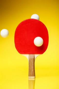 Red side of a ping pong racket with three white balls in the air, standing .. Stock Photos