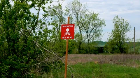 Red sign Danger, mines warns of danger in the field near the road Stock Footage 240702482