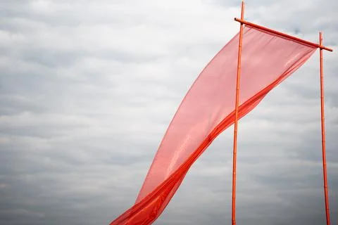 Red silk fabric develops against the background of white clouds Stock Photos