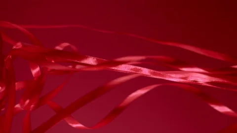 Red silk shiny ribbons falling down on a matte background. 4k quality vertical Stock Footage 144324224