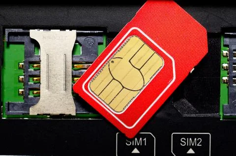 Red SIM card on slots in mobile phone. Stock Photos