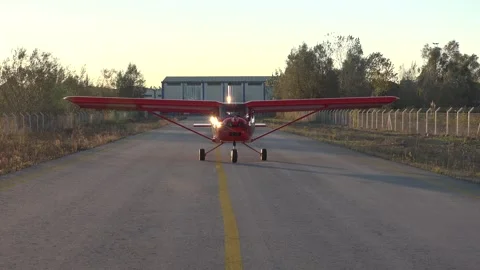Red single engine airplane taxiing from hangar toward airstrip on airport runway Stock Footage 339586659