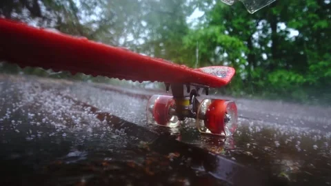 Red skateboard in the rain Stockbeeldmateriaal 154428311