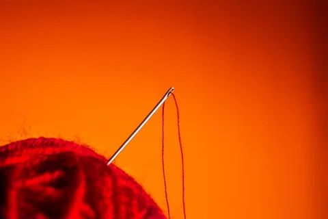 Red skein of thread thrust needle on lush lava background. close up copy space Foto stock