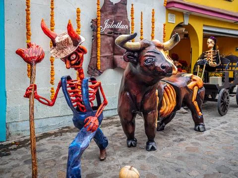 A red skeleton, a bull pulling a cart on which sits the skeleton of a woman Stock Photos