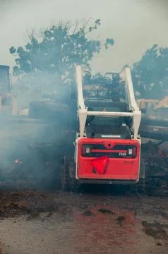 Red Skid Steer Loader in Dense Smoke at Construction Site Stock Photos